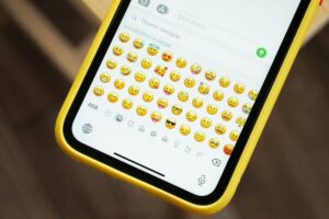 iPhone jaune affichant de nombreux emojis sur le clavier